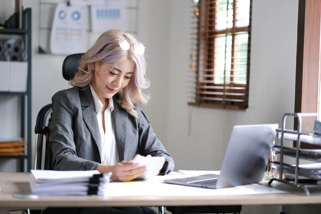 Young Asian businesswoman using a calculator to calculate business principles.